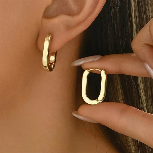 Boucle D'oreille Rectangulaire Géométrique Acier inoxydable, portée par une femme, elle présente l'autre boucle d'oreille entre ses doigts