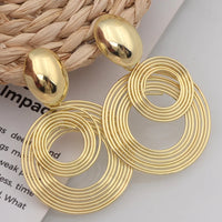 Boucle d'Oreille Doré et Ronde au Design Original sur une table blanche