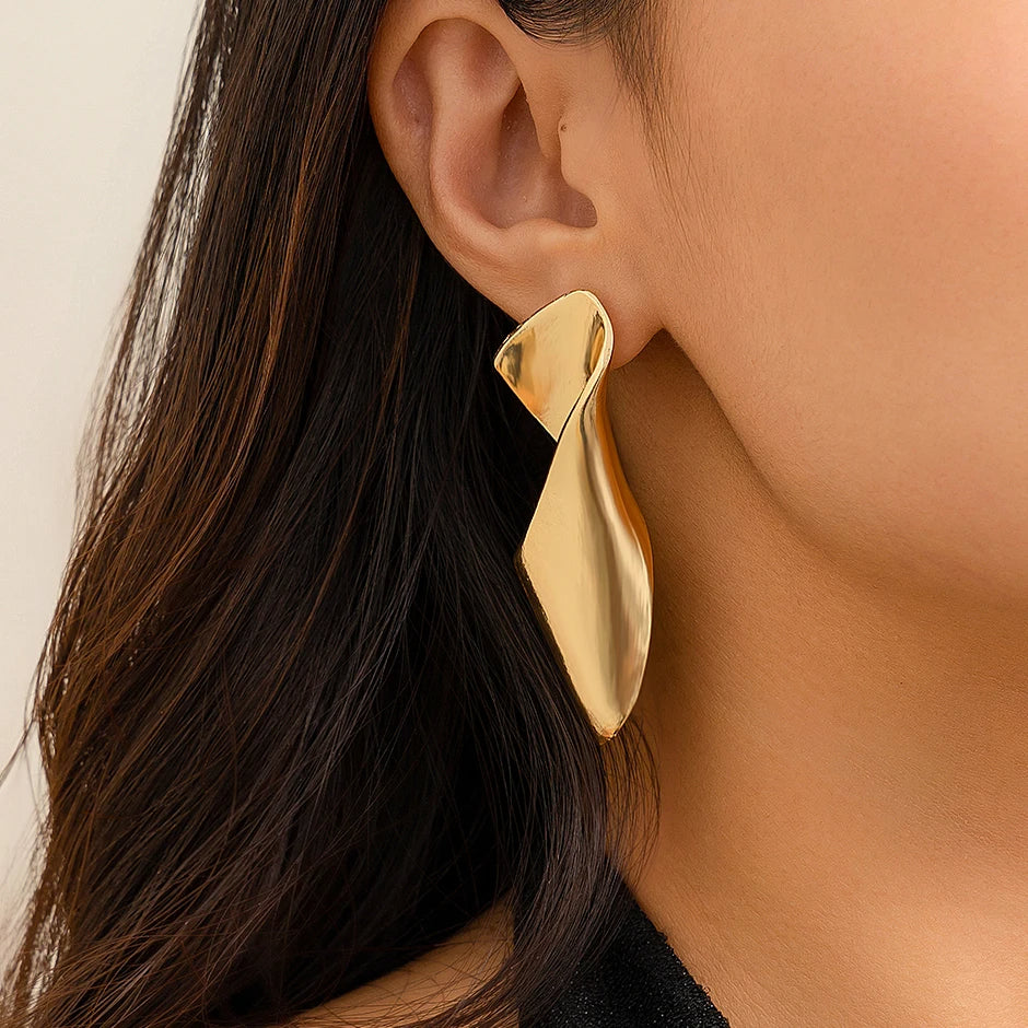 Boucle d'Oreille Doré Torsadée et Élégante portée par une femme Image