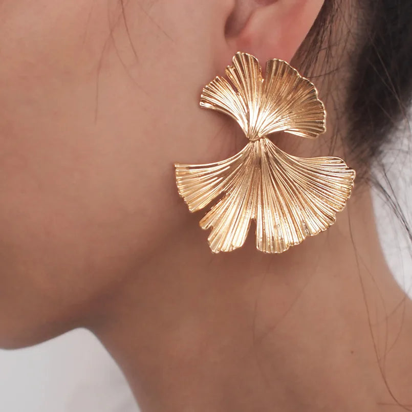 Boucle d'Oreille Feuille Dorée Sophistiquée portée par une femme de profil Image