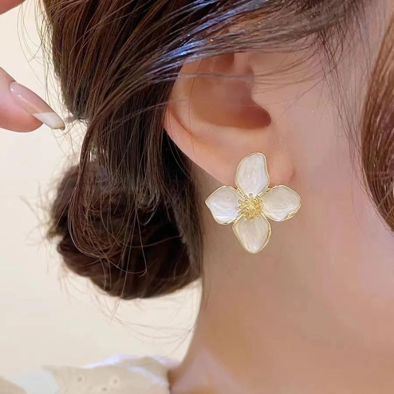 Boucle D'oreille Fleur Hibiscus Blanc, porté par une mannequin, on ne voit que son oreille, ses cheveux et son cou.