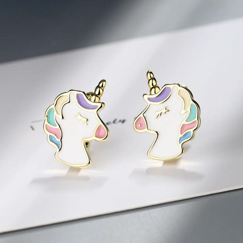 Boucle D'oreille Licorne Dorée Mignonne, la paire est posée sur une enveloppe blanche.