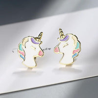 Boucle D'oreille Licorne Dorée Mignonne, la paire est posée sur une enveloppe blanche.