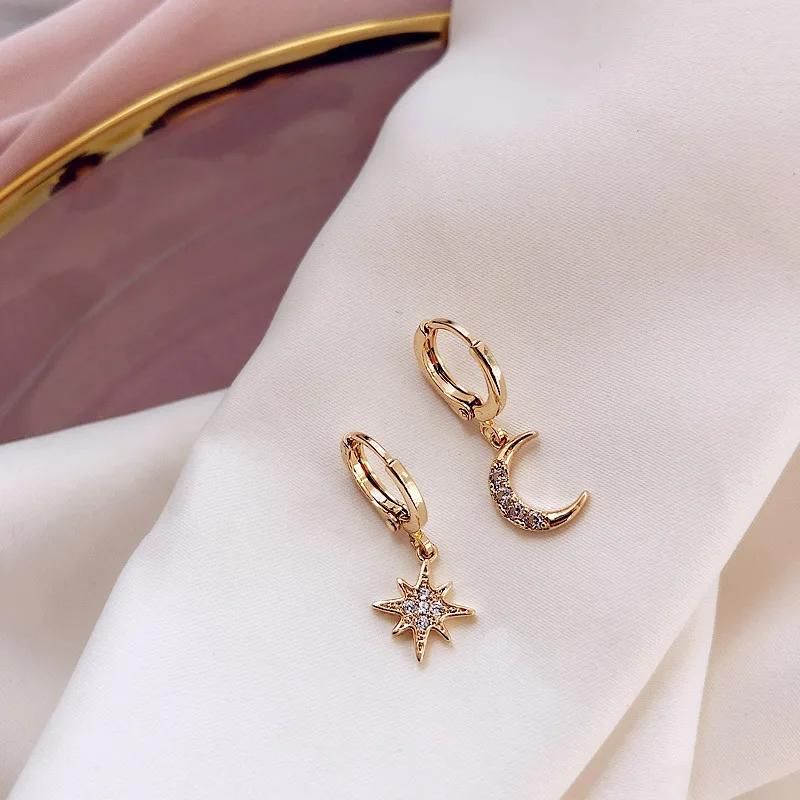 Boucle D'oreille Lune et Étoile, posées sur un linge blanc, elles sont montées sur créoles. Image