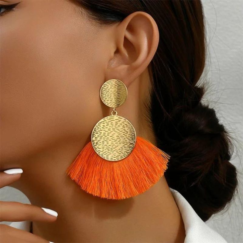 Boucle D'oreille Orange et Dorée Pendante, portée par une femme, on voit son visage de profil et son coup.