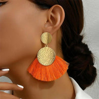 Boucle D'oreille Orange et Dorée Pendante, portée par une femme, on voit son visage de profil et son coup.