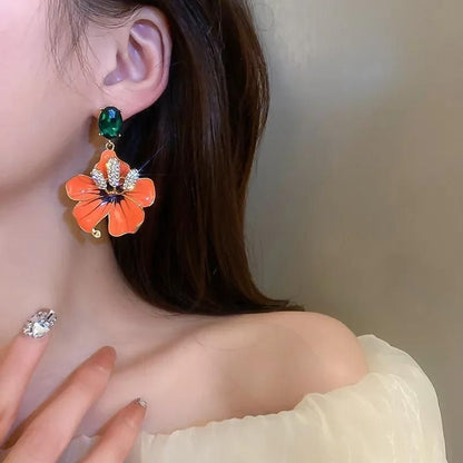 Boucle D'oreille Orange Fleur, porté par une mannequin, on ne voit que son oreille, son cou et le haut de son épaule