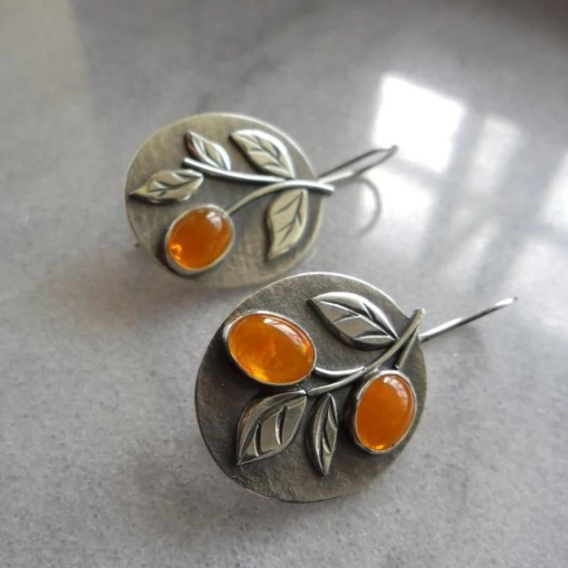 Boucle D'oreille Orange Vintage Plante posées sur du marbre gris.