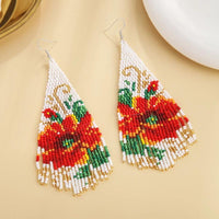 Boucles D'oreilles Originales Grand Triangle Perles, blanches, posées sur un fond beige.