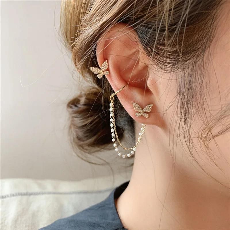 Boucle D'oreille Papillon Dépareillée avec Chaine, portées par une mannequin, on voit son oreille son cou et ses cheveux attachés en chignon.