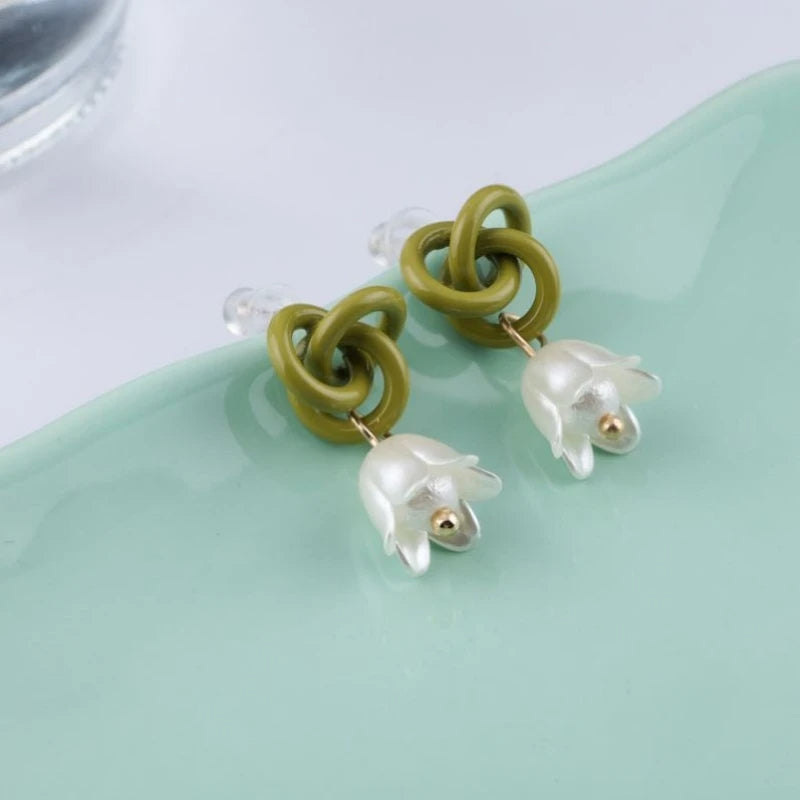 Boucle d'Oreille Verte Tendance en Design de Fleur posée sur du verre Image