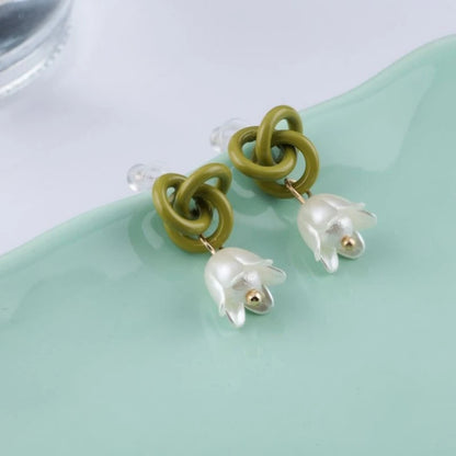 Boucle d'Oreille Verte Tendance en Design de Fleur posée sur du verre