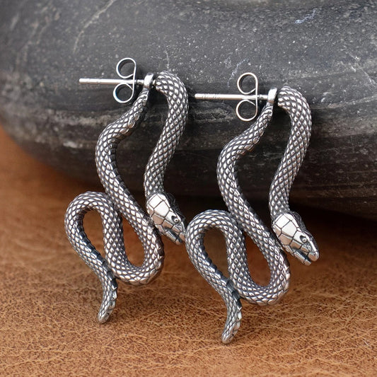 Boucle d'Oreille Viking Homme Serpent posée sur du bois