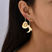 Boucles D'oreilles Asymétriques Cowboy, portées sur la même oreille par une femme, on ne voit que son oreille et le haut de son coup.