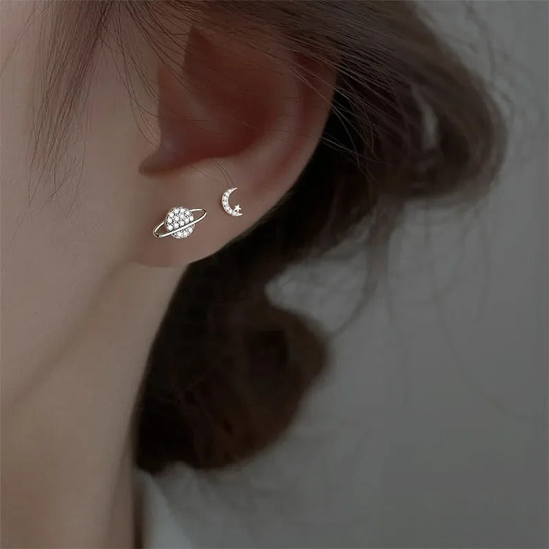 Boucles D'oreilles Asymétriques Galaxie Acier Inoxydable, les deux porté sur la même oreille d'une jeune femme.