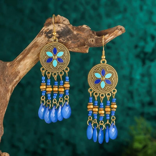 Boucles D'oreilles Originales Style Attrape Rêve bleue et dorées, suspendues sur une branche d'arbre