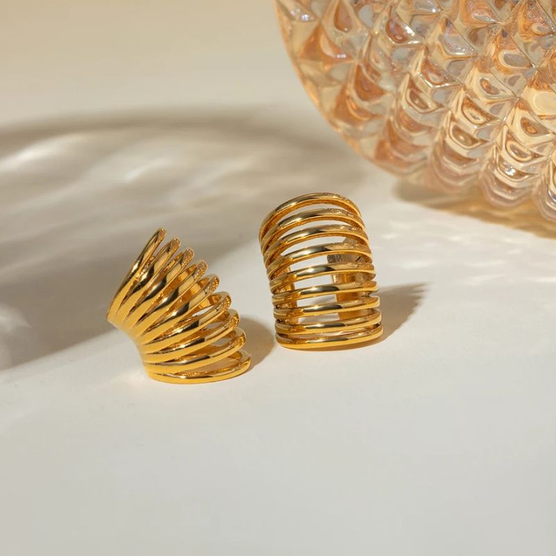 Ear cuff Effet Ressort En Acier Inoxydable, 2 pièces, posé sur une table blanc cassé.