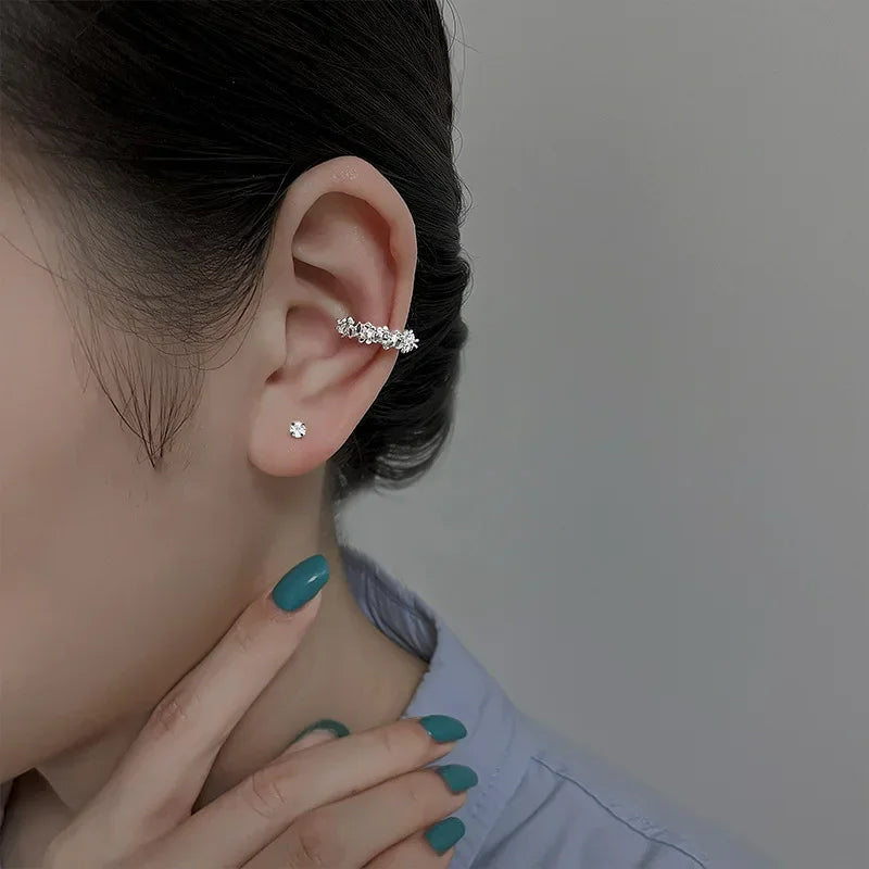 Ear cuff Irrégulier Effet Floral, argenté porté par une femme, avec une boucle d'oreille puce en plus à son oreille.
