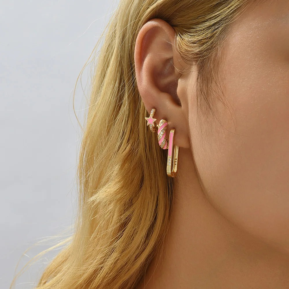 Lot 3 Paires Boucles D'oreilles Dorées et Roses, portées par une femme, on ne voit qu'une de ses oreilles qui porte 3 boucles différentes