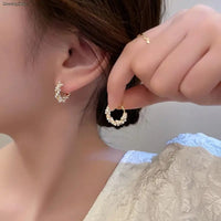 Petite Boucle d'Oreille Minimaliste une dans une main une sur l'oreille