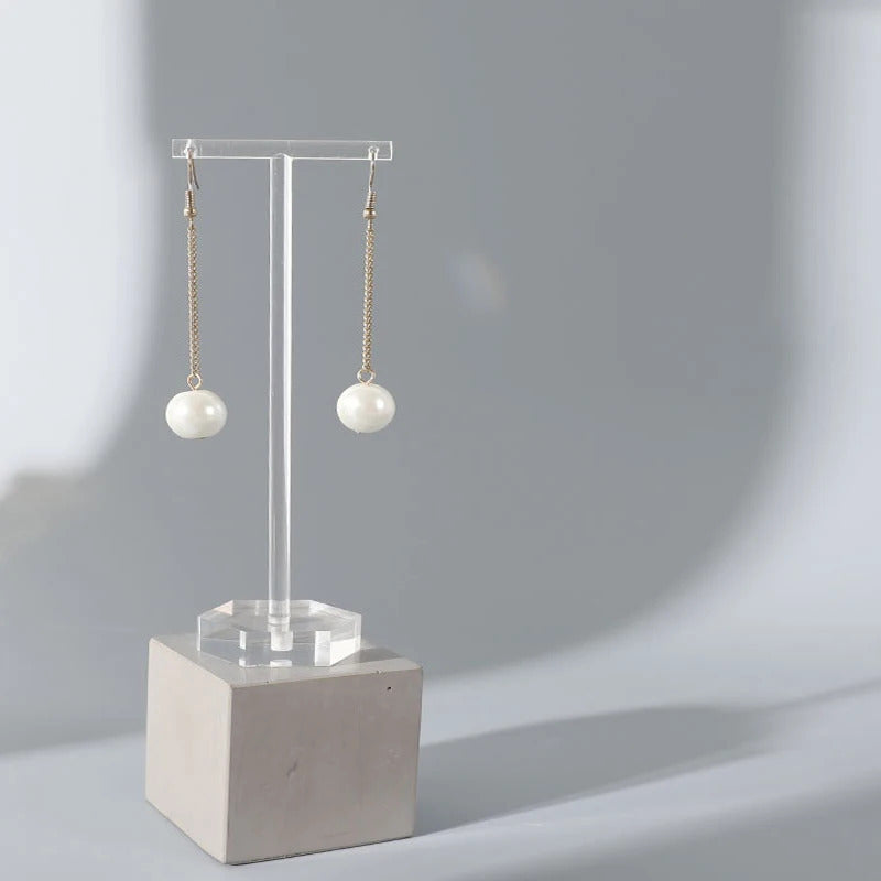 Porte Boucle D'oreille en Acrylique Transparent en Forme de T sur un bloc de pierre de forme carré sur fond gris Image