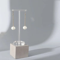 Porte Boucle D'oreille en Acrylique Transparent en Forme de T sur un bloc de pierre de forme carré sur fond gris